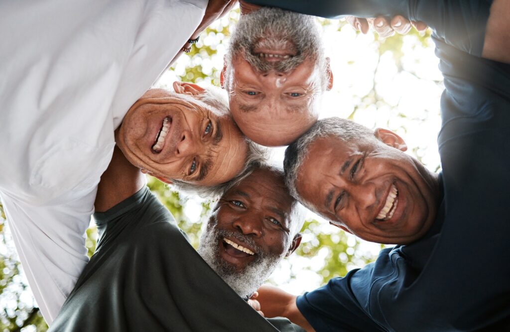 Senior men, friends and community together in a circle for support, trust and diversity with a smil